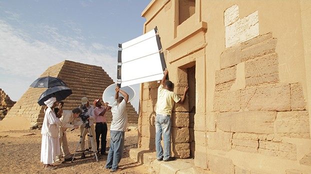 Film crew with reflectors and parasols at a temple in front of the pyramids of Meroë