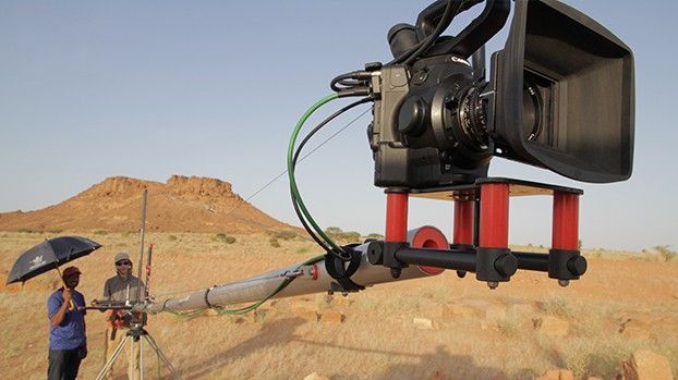 Camera on a crane in the desert, crew under a parasol