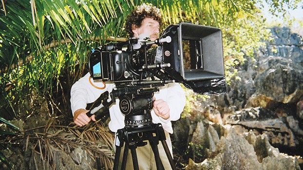 Cameraman at a 35 mm film camera among limestone pinnacles and palm trees