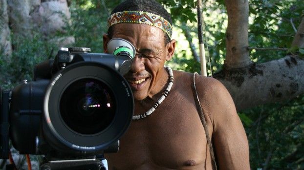 Homme souriant portant un bandeau regardant dans le viseur d’une grande caméra