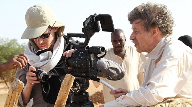 Camera assistant changing the lens, next to the director and a local guide