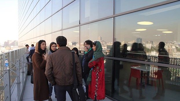 People talking on the balcony of a glass high-rise above the city