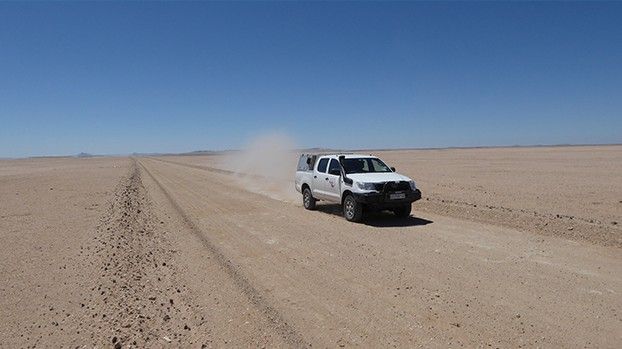 Off-road vehicle on a sandy track across a vast desert plain