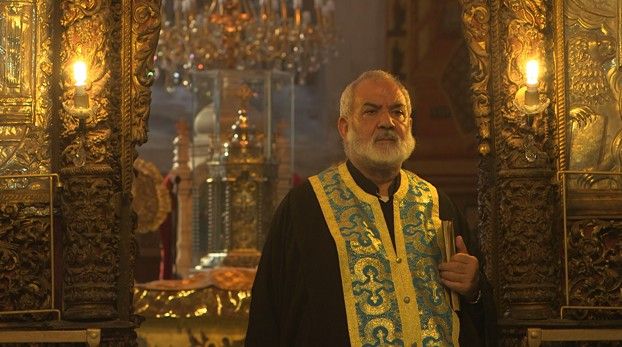Ecclésiastique à barbe blanche en habit brodé d’or dans une église richement décorée