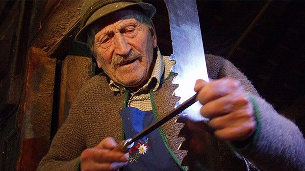 Old man in a hat sharpening a saw blade