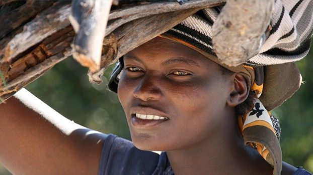 Smiling woman carrying a bundle of wood on her head