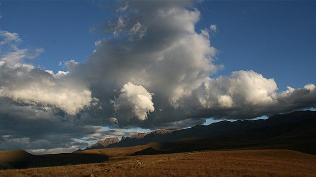 Towering clouds above a wide plain with a mountain range