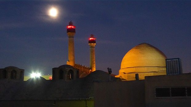 Illuminated dome and minarets of the Friday Mosque under a full moon